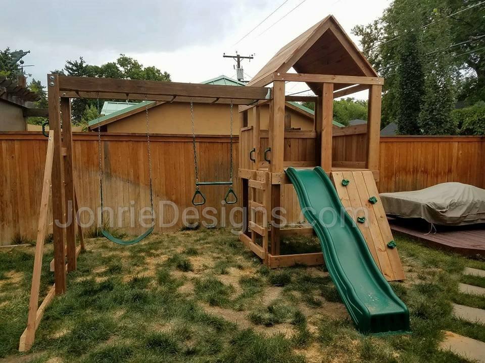 5'x5' Clubhouse with wooden roof, 4' Deck height, Standard slide, Rock wall entry, 8' Monkey bars with dual ladders, Standard swing & Trapeze bar
